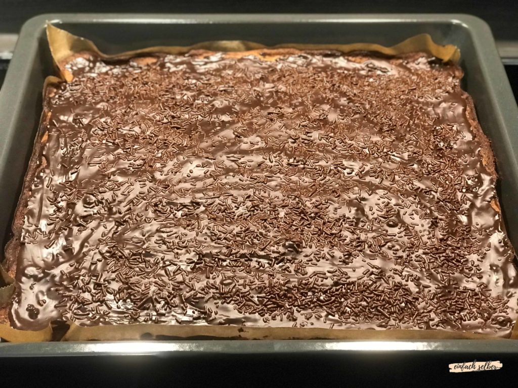 Schokoladenglasur mit Schokostreusel auf dem Schokoladenkuchen vom Blech